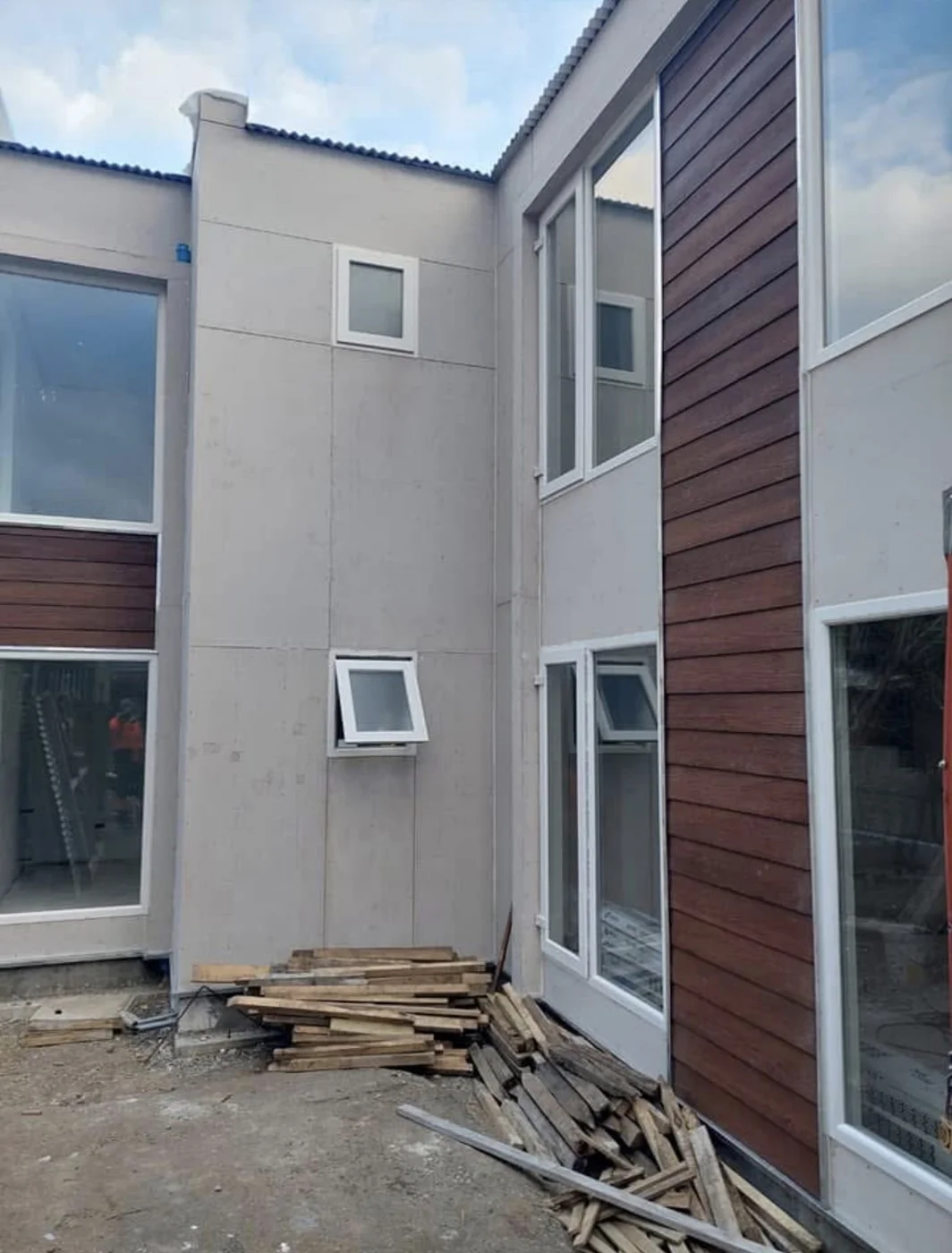 Ventanas blancas verticales sobre fachada gris y roja